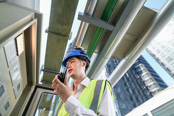 Industrial engineer adjusting pipeline valve with radio communication on construction site....