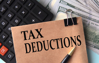 TAX DEDUCTIONS - words on brown paper on the background of calculator and banknotes