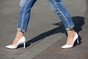 Stiletto heels, female legs in high-heeled shoes. Woman in jeans walking down the a city street