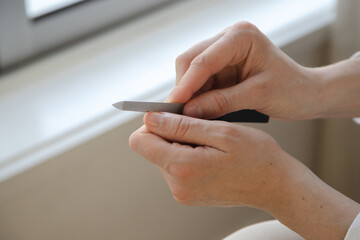 A person carefully filing their nails at home, focusing on self-care and grooming. Close up