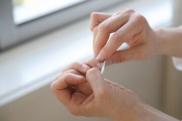 A person carefully filing their nails at home, focusing on self-care and grooming.