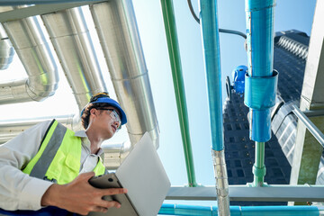 Industrial engineer adjusting pipeline valve with radio communication on construction site....