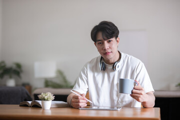 Young Asian student doing homework and studying online, online video call on laptop happily at home