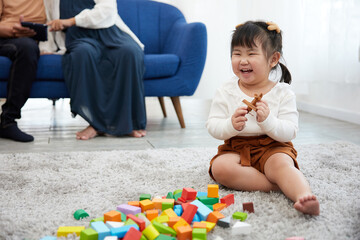 child girl feeling happy and playing with colorful toy blocks on the carpet floor