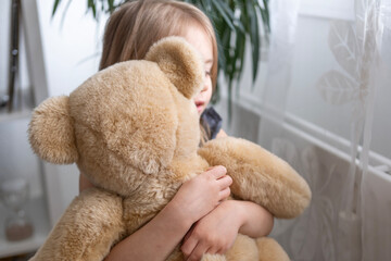 little child, blonde girl 4 years old plays with toy, hugs teddy bear, happy childhood, first...