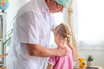 male Orthopedist doctor conducts spinal examination child, young girl shows signs scoliosis, spine...