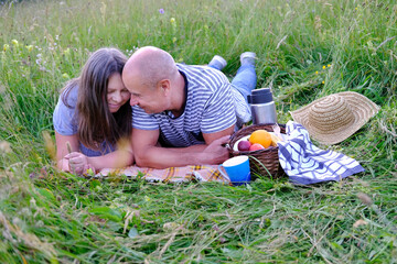 mature man 60 years old, woman 50 years old in blue clothes lie on grass in meadow, next to picnic...