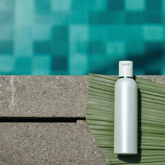 Bottle of cosmetic product near swimming pool