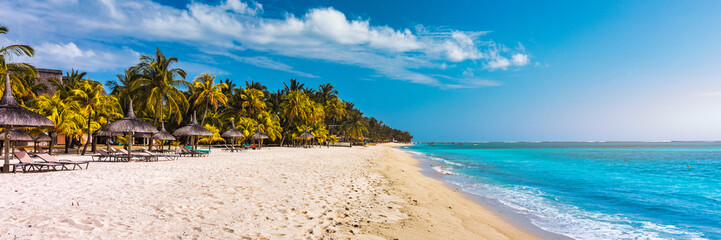 A beach with palm trees and umbrellas on Le morne Brabant beach in Mauriutius. Tropical crystal ocean with Le Morne beach and luxury beach in Mauritius. Le Morne beach with palm trees, white sand