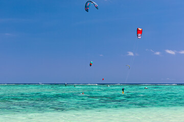 Kite surfers in the waters of Indian Ocean, Mauritius. Kite surfing in the clear waters of the...