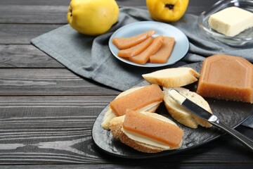 Tasty sandwiches with quince paste served on black wooden table, space for text
