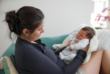 Mother holding her newborn, both looking tired, capturing the raw emotions and challenges of early...