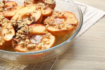Delicious baked quinces with nuts and honey in bowl on wooden table, closeup