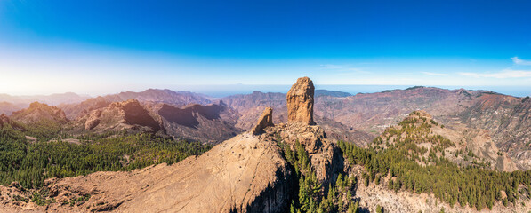Roque Nublo and Pico de Teide in the background on Gran Canaria Island, Spain. Panoramic view of Roque Nublo sacred mountain, Roque Nublo Rural Park, Gran Canary, Canary Islands, Spain.