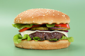 Burger with delicious patty on green background, closeup