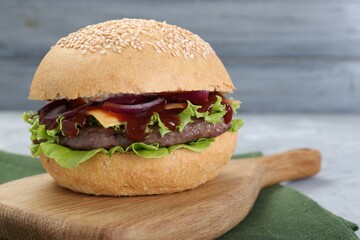 Delicious cheeseburger with lettuce, onion, ketchup and patty on table, closeup
