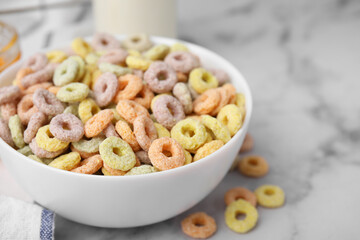 Tasty cereal rings in bowl on white marble table, closeup. Space for text
