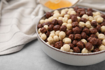 Tasty cereal balls in bowl on grey table, closeup. Space for text