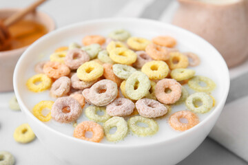 Cereal rings and milk in bowl on white table, closeup