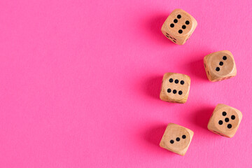 Many wooden game dices on pink background, flat lay. Space for text