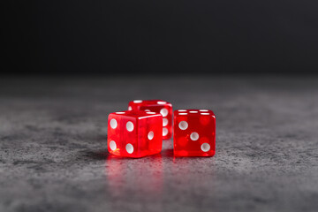 Three red game dices on grey textured table