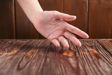 Woman holding hand above wooden table, closeup. Space for text