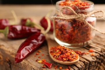 Chili pepper flakes and pods on wooden table, closeup. Space for text