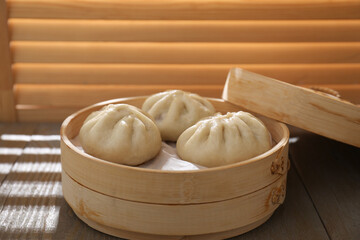Delicious bao buns (baozi) on wooden table, closeup