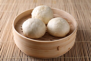 Delicious Chinese steamed buns on bamboo mat, closeup