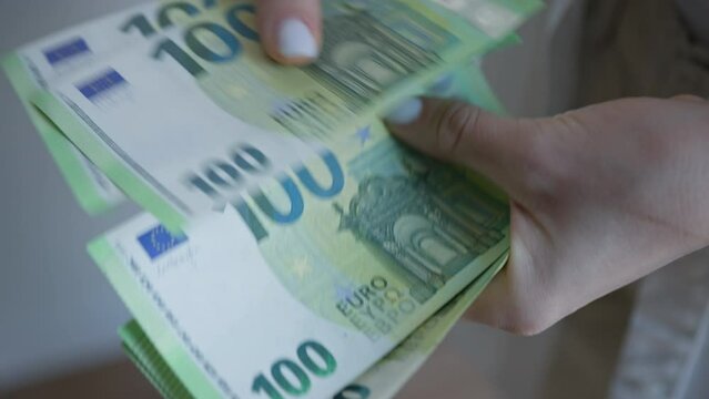 Detailed View of a Woman's Hands Holding New 100 Euro Bills, Illustrating Modern European Currency and Financial Exchange