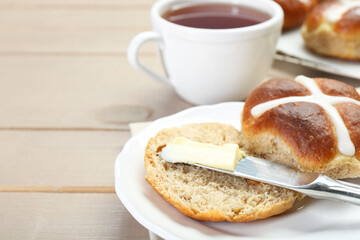 Tasty hot cross bun served on wooden table, closeup. Space for text