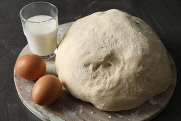 Raw dough, eggs and milk on black table, closeup