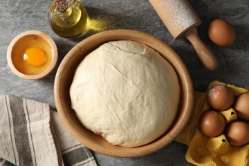 Raw dough, rolling pin and ingredients on grey table, flat lay