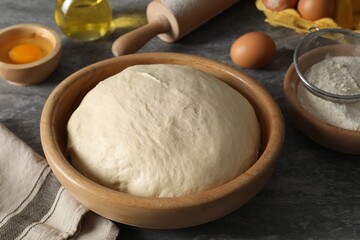 Raw dough, rolling pin and ingredients on grey table