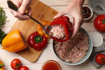 Woman making stuffed peppers with ground meat at white wooden table, top view