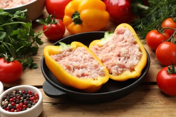 Raw stuffed peppers with ground meat and ingredients on wooden table