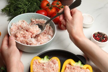 Woman making stuffed peppers with ground meat at white table, closeup