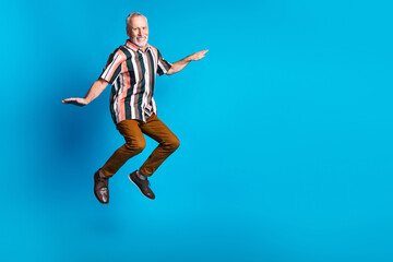 Fototapeta na wymiar Photo of positive smiling retired man wear striped stylish clothes fly air blank space isolated on blue color background