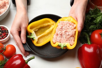 Woman making stuffed peppers with ground meat at white table, closeup