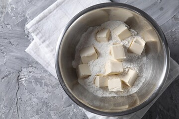 Making shortcrust pastry. Flour and butter in bowl on grey table, top view
