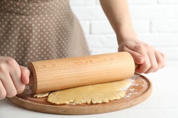 Making shortcrust pastry. Woman rolling raw dough at white wooden table, closeup