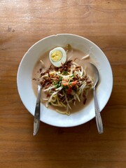 Celor noodles typical of South Sumatra, Indonesia, on a white plate on a wooden table with natural lighting