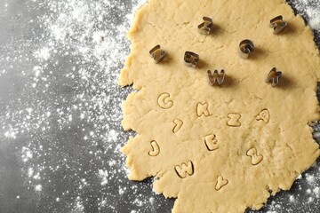 Making shortcrust pastry. Raw dough and cookie cutters on grey table, top view. Space for text