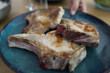 Three juicy pork chops on a blue plate, cooked to perfection with a golden-brown crust and a hint...