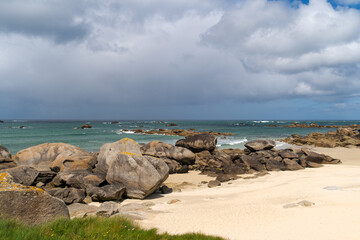 Des rochers massifs parsèment une plage du nord du Finistère en Bretagne sous un ciel nuageux, offrant une vue côtière sauvage.