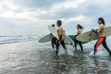Friends gather on the sea shore, preparing their surfboards and soaking in the vibrant energy of...
