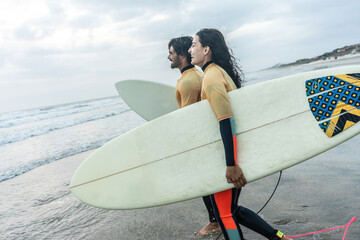 Two friends sprint toward the water. Boards in hand, wetsuits on, they're poised for a ride through the waves, creating unforgettable memories together.	