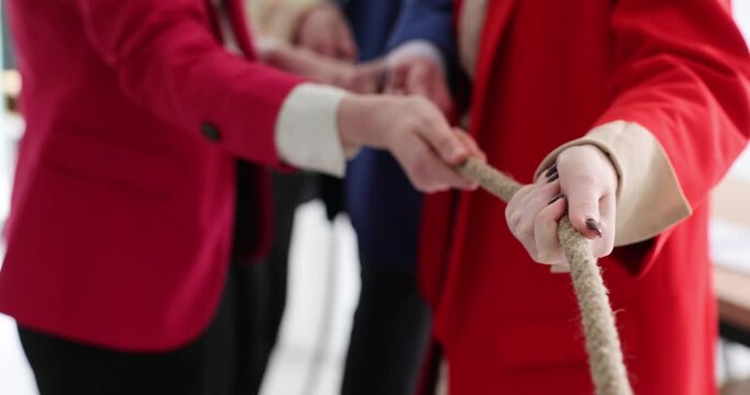 Employees in colorful jackets pull rope together and have fun at team-building break. Collective develops teamwork skills in spacious light premise slow motion