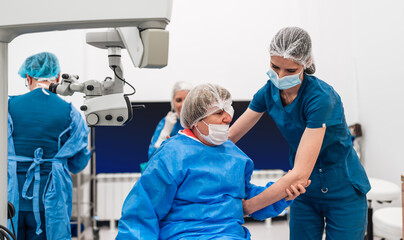 Skilled female surgeon and his medical team performs precise eye surgery on an elderly patient,...