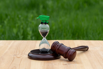 Hourglass, judge's gavel and miniature shopping cart from a supermarket on a wooden surface